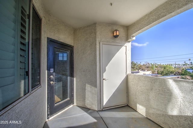 entrance to property with a balcony and stucco siding