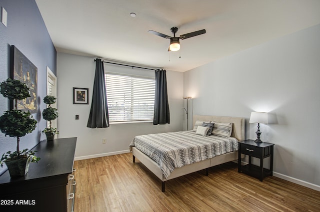 bedroom with a ceiling fan, baseboards, and wood finished floors