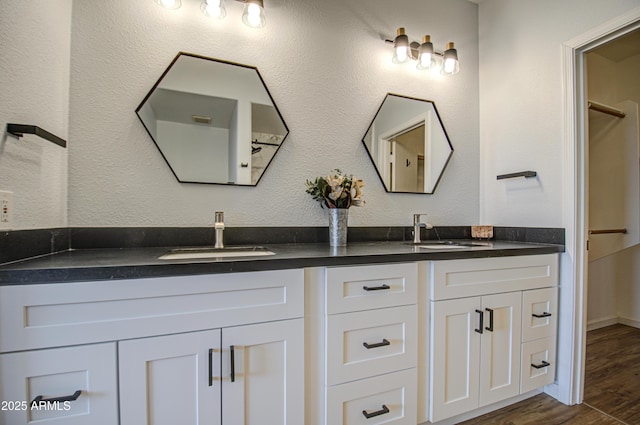 full bath featuring double vanity, a sink, and wood finished floors