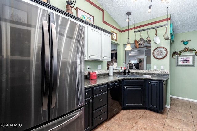 kitchen featuring sink, a textured ceiling, lofted ceiling, white cabinets, and stainless steel fridge