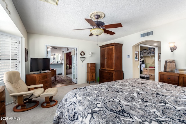 bedroom featuring ceiling fan, light carpet, a textured ceiling, and a closet