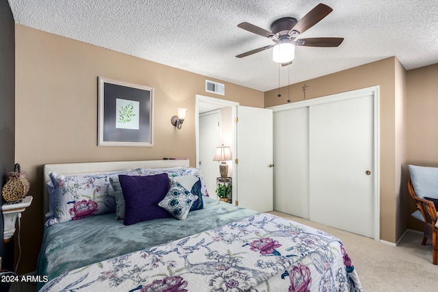 bedroom with ceiling fan, carpet, a textured ceiling, and a closet