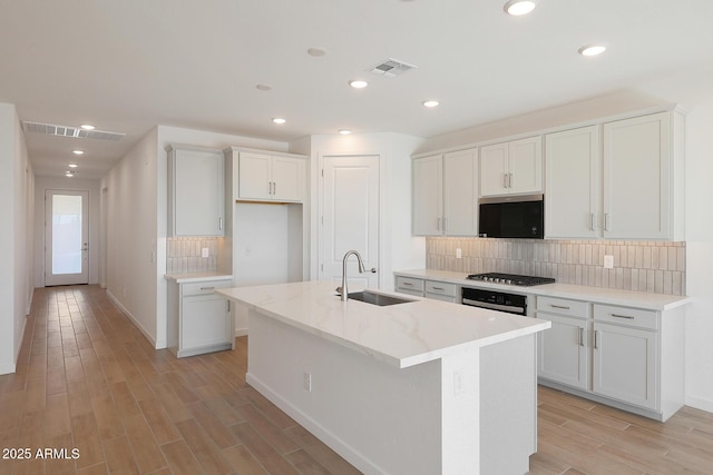 kitchen featuring backsplash, white cabinets, and a center island with sink