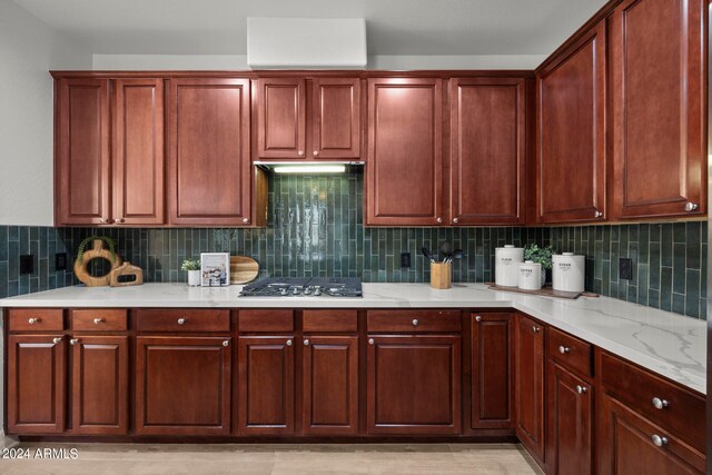 kitchen featuring black gas cooktop, light stone counters, and tasteful backsplash