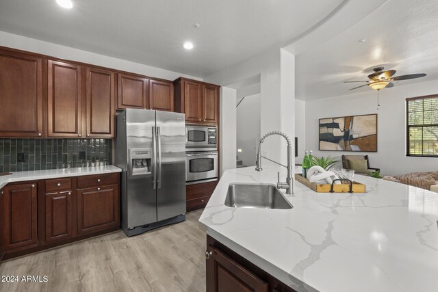 kitchen featuring light stone counters, light hardwood / wood-style floors, stainless steel appliances, and sink