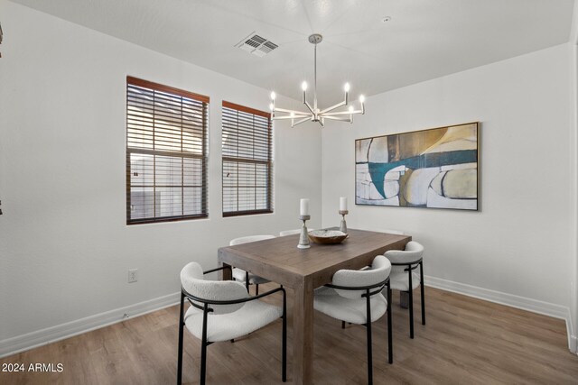 dining space with hardwood / wood-style flooring and a chandelier