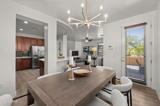 dining area with light hardwood / wood-style flooring and ceiling fan with notable chandelier