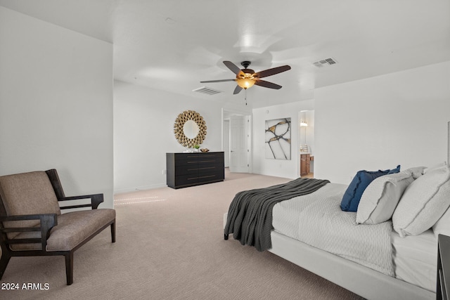 bedroom featuring light carpet, ceiling fan, and ensuite bath