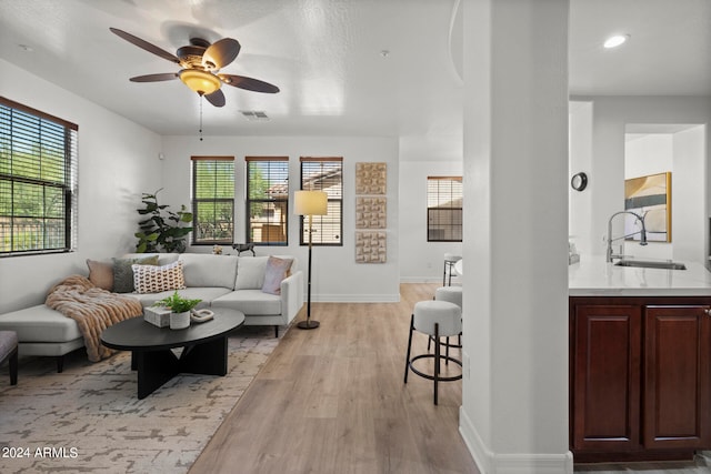 living room featuring ceiling fan, light hardwood / wood-style floors, plenty of natural light, and sink