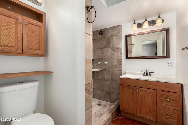 bathroom featuring vanity, toilet, and tiled shower