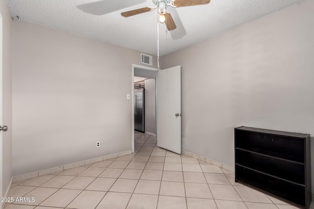 unfurnished bedroom featuring light tile patterned floors, a ceiling fan, visible vents, stainless steel refrigerator, and a textured ceiling