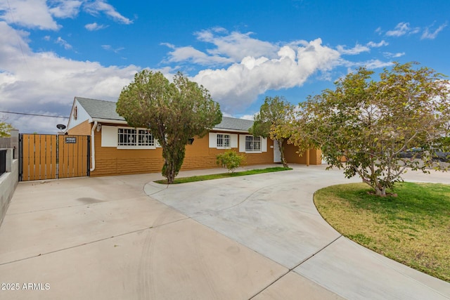 ranch-style house with fence, concrete driveway, a front lawn, and a gate