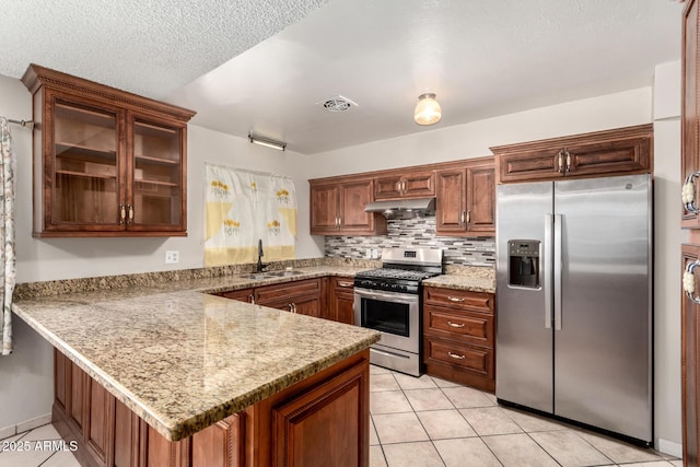 kitchen featuring visible vents, a peninsula, a sink, stainless steel appliances, and under cabinet range hood