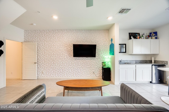 living room featuring light tile patterned floors, visible vents, baseboards, and wallpapered walls