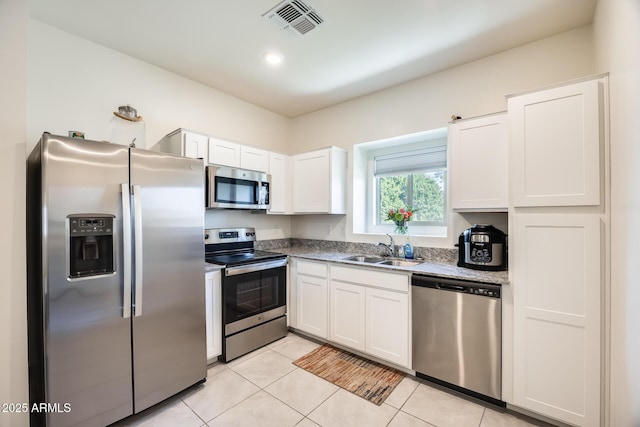 kitchen with light tile patterned floors, stainless steel appliances, a sink, visible vents, and white cabinetry