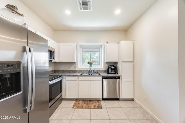 kitchen with stainless steel appliances, visible vents, light tile patterned flooring, a sink, and white cabinetry