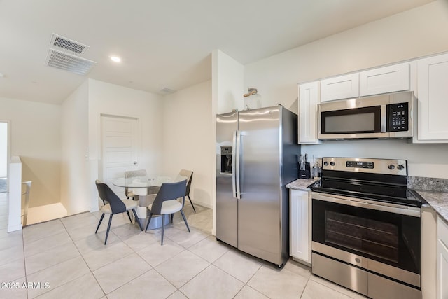 kitchen with stainless steel appliances, light tile patterned floors, visible vents, and white cabinetry