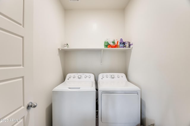 washroom with laundry area, visible vents, and washer and dryer