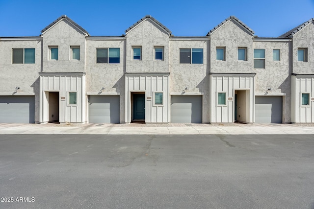 multi unit property with a garage, a tiled roof, board and batten siding, and stucco siding