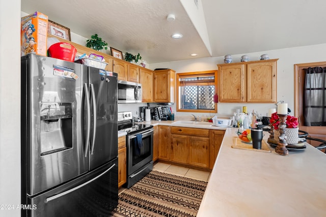 kitchen featuring a textured ceiling, light tile patterned flooring, sink, and stainless steel appliances