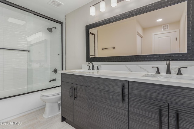 full bathroom with vanity, shower / bath combination with glass door, and toilet