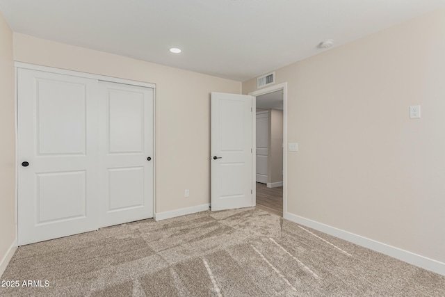 unfurnished bedroom with light colored carpet and a closet