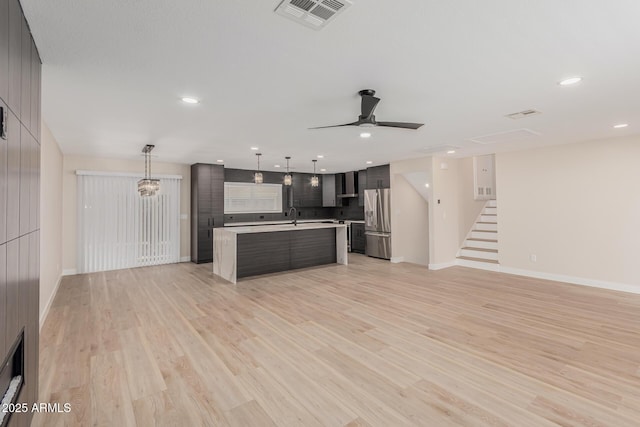 kitchen featuring a kitchen island, pendant lighting, stainless steel fridge, wall chimney range hood, and light wood-type flooring