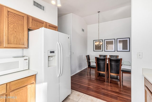 8566 N 108th Ln, Peoria, AZ 85345 - kitchen featuring white appliances, a chandelier, light countertops, lofted ceiling, and light tile patterned flooring