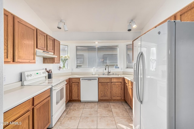 8566 N 108th Ln, Peoria, AZ 85345 - kitchen with white appliances, under cabinet range hood, light tile patterned flooring, and brown cabinets
