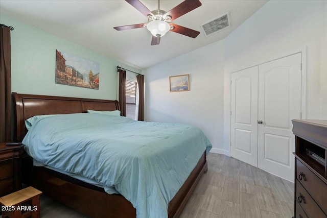 bedroom featuring vaulted ceiling, light hardwood / wood-style flooring, ceiling fan, and a closet