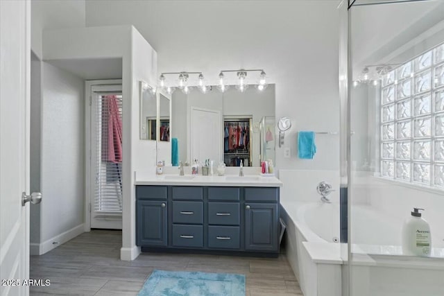 bathroom with a healthy amount of sunlight, a tub to relax in, and vanity