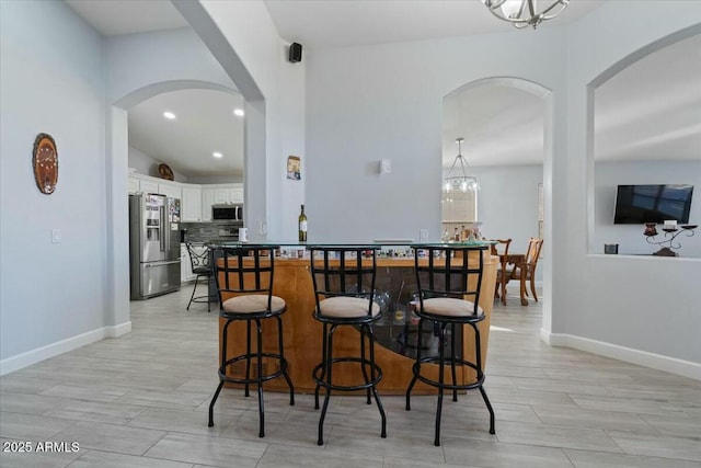 kitchen featuring appliances with stainless steel finishes, decorative light fixtures, tasteful backsplash, white cabinetry, and an inviting chandelier