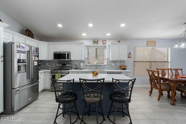 kitchen featuring pendant lighting, stainless steel appliances, sink, and white cabinets