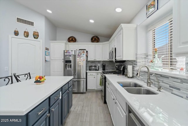 kitchen with lofted ceiling, sink, stainless steel appliances, and white cabinets