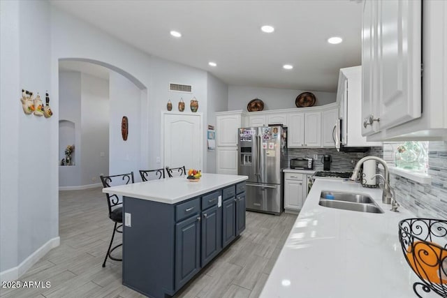 kitchen featuring appliances with stainless steel finishes, white cabinetry, sink, a kitchen breakfast bar, and a center island