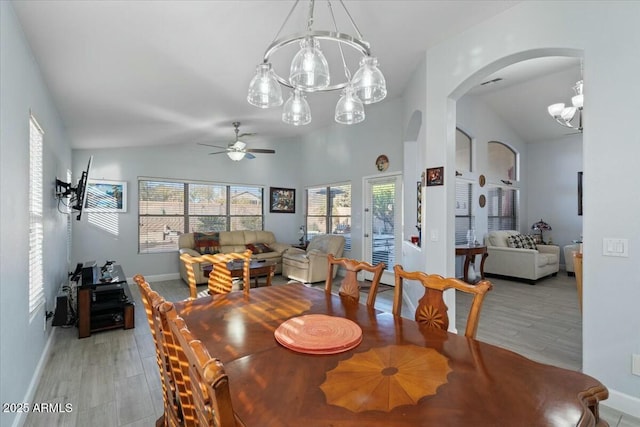 dining area with ceiling fan with notable chandelier, vaulted ceiling, and light hardwood / wood-style floors