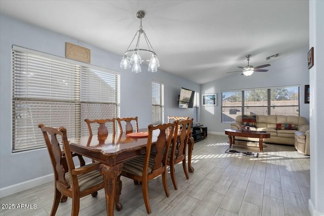 dining area featuring vaulted ceiling and ceiling fan with notable chandelier