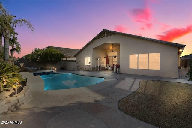 pool at dusk featuring a patio and ceiling fan