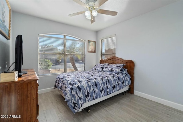 bedroom with ceiling fan, light hardwood / wood-style floors, and multiple windows