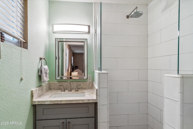 bathroom featuring a tile shower and vanity