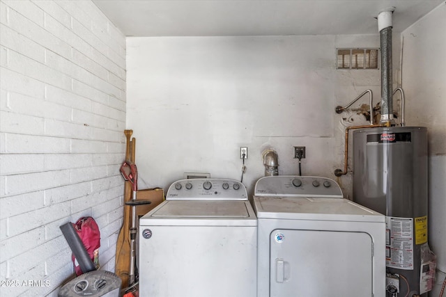 clothes washing area featuring gas water heater and separate washer and dryer