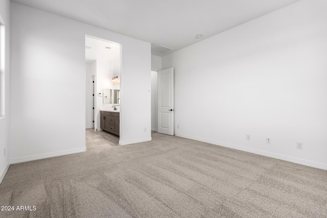 unfurnished bedroom with connected bathroom and light colored carpet