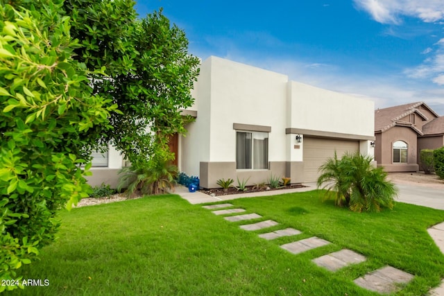 pueblo revival-style home featuring a front yard and a garage