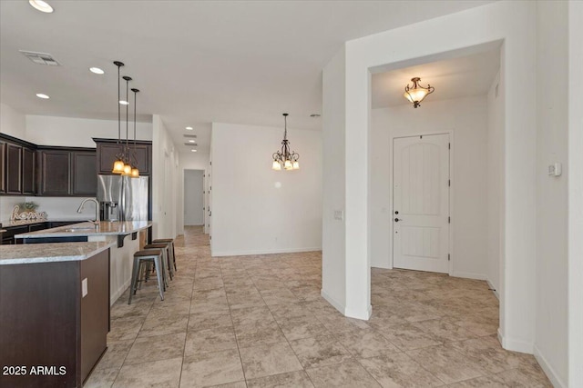 2145 N 88th St, Mesa, AZ 85207 - kitchen with a breakfast bar area, visible vents, dark brown cabinetry, an inviting chandelier, and stainless steel fridge
