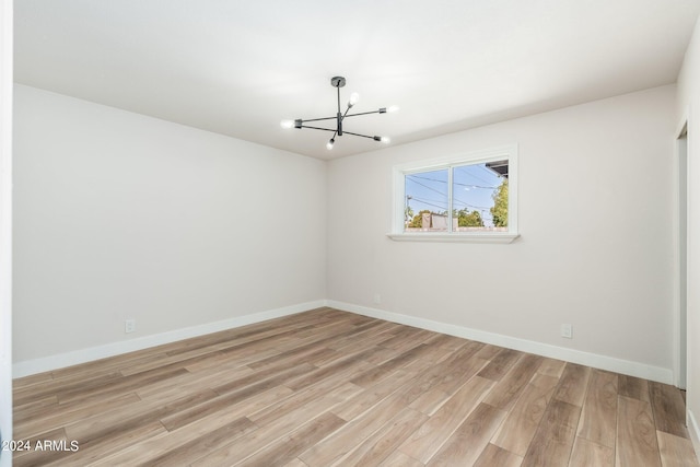 unfurnished room featuring light hardwood / wood-style floors and a notable chandelier