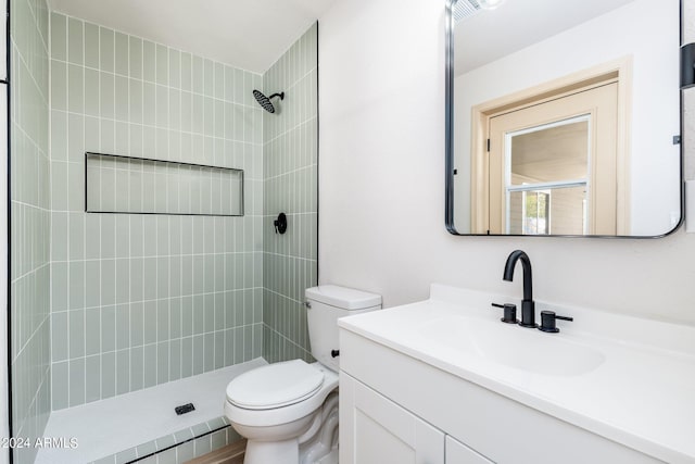 bathroom with toilet, vanity, and a tile shower