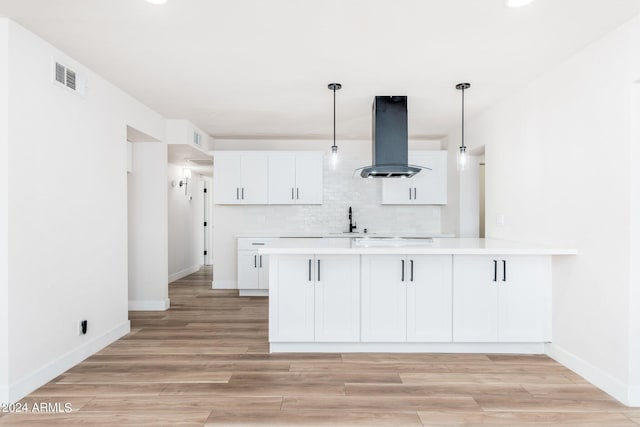 kitchen featuring island exhaust hood, kitchen peninsula, pendant lighting, and white cabinets