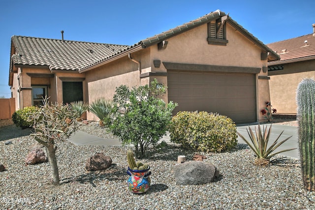 view of front of property with stucco siding, driveway, an attached garage, and a tile roof