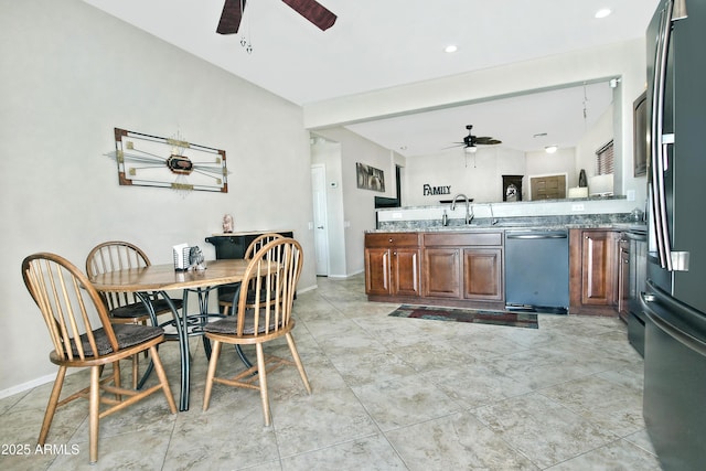 kitchen featuring baseboards, a peninsula, stainless steel appliances, a ceiling fan, and a sink