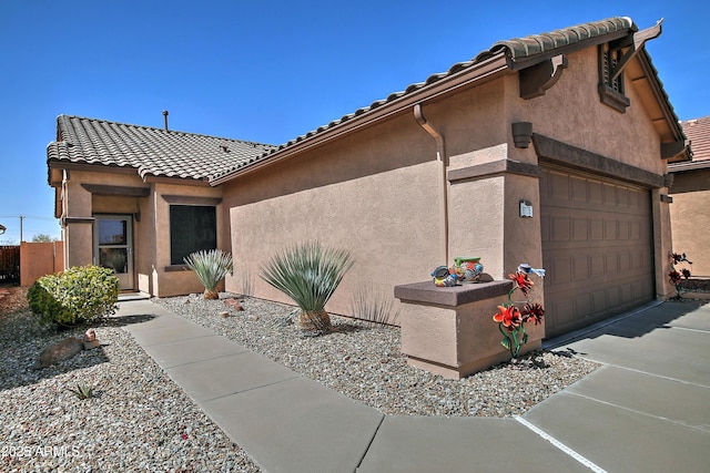 view of front of property with a tile roof, an attached garage, and stucco siding